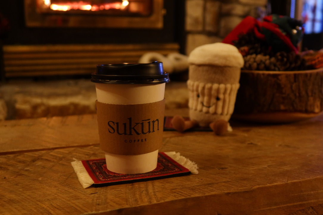 Sukūn coffee cup resting on a red carpet coaster